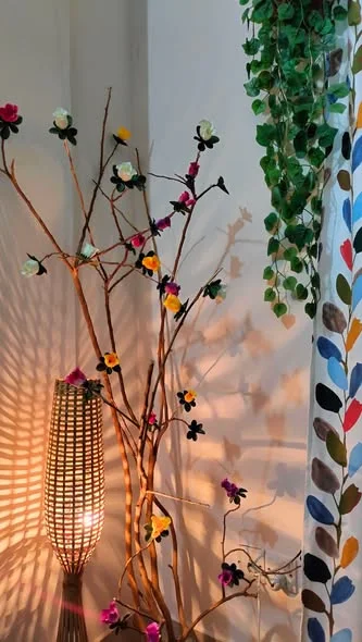 A tall bamboo lamp glowing beside flowering branches, from a customer's home